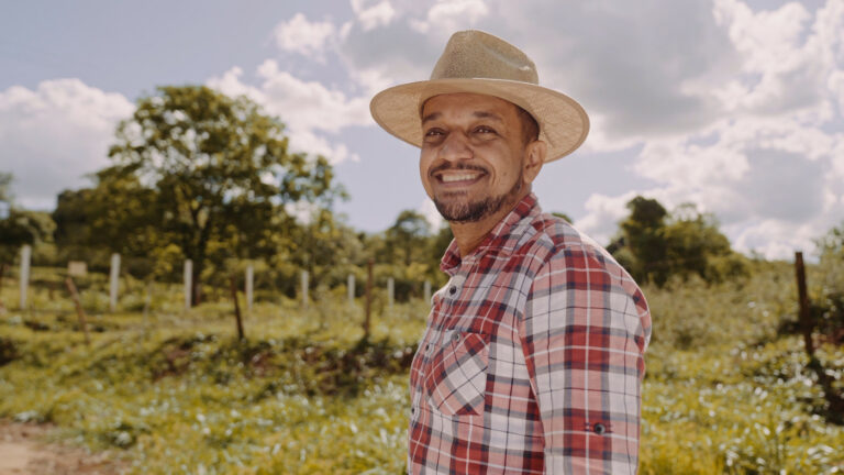 Portrait of young farmer man in the casual shirt and hat in the farm
